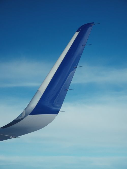 Free A vertical shot of a blue airplane wing against a clear blue sky, capturing the essence of air travel. Stock Photo