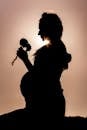 Silhouette of Woman Holding Microphone during Sunset
