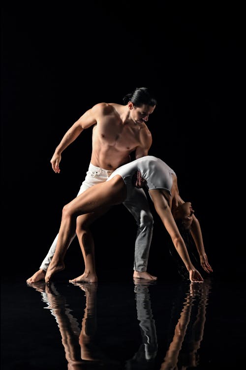 Performers in a Dance Pose Reflecting in the Water Beneath Their Feet