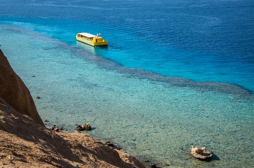 Free Yellow tour boat sailing on pristine blue sea, offering a perfect summer leisure scene. Stock Photo