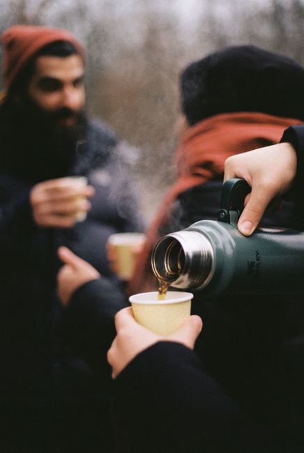 People enjoying hot drinks outdoors in Berlin during winter, creating a cozy moment.