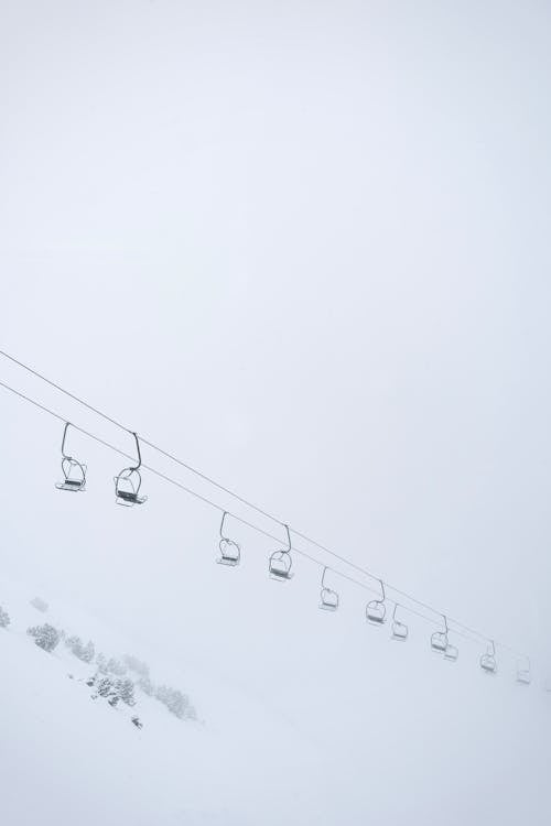 Ski Lift Seats Hanging on Cables over a Snowy Mountain Slope