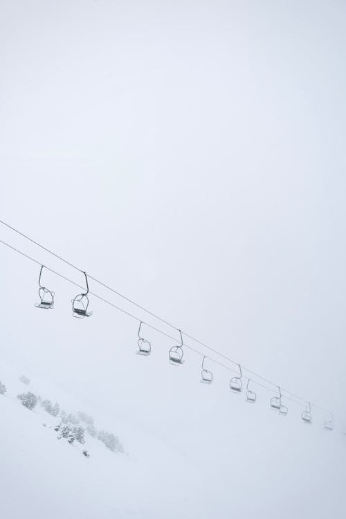 Ski Lift Seats Hanging on Cables over a Snowy Mountain Slope