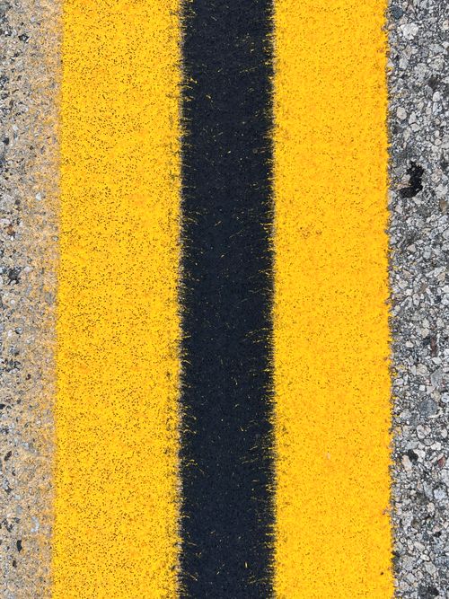 Free Detailed view of yellow and black road markings on an asphalt surface. Stock Photo