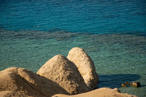 Free Breathtaking view of clear blue waters and sandy rock formations along a serene coast. Stock Photo