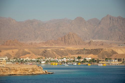 Free A scenic view of a coastal town with a stunning mountain backdrop. Stock Photo