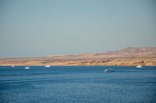 Free Peaceful coastal landscape showcasing boats on a vast blue ocean with distant mountains. Stock Photo