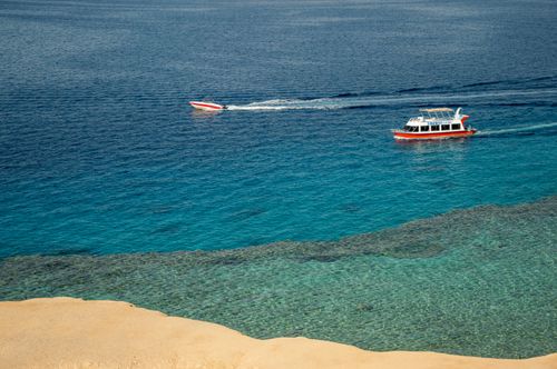 Free Aerial view of boats cruising on clear blue waters near a sandy shore. Stock Photo