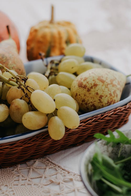 Grapes and Pear in Wicker Basket on Table