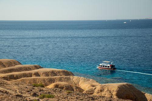 Free A motorboat navigates along a captivating barren coastline with azure blue waters, perfect for relaxation and travel. Stock Photo