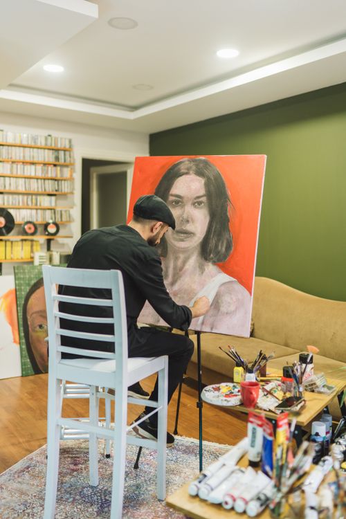 Free Male artist painting in a modern studio, working on a large canvas portrait. Stock Photo