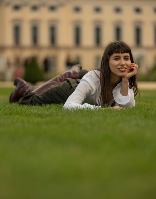 Free A young woman lying on the grass in a Berlin park, smiling warmly. Stock Photo