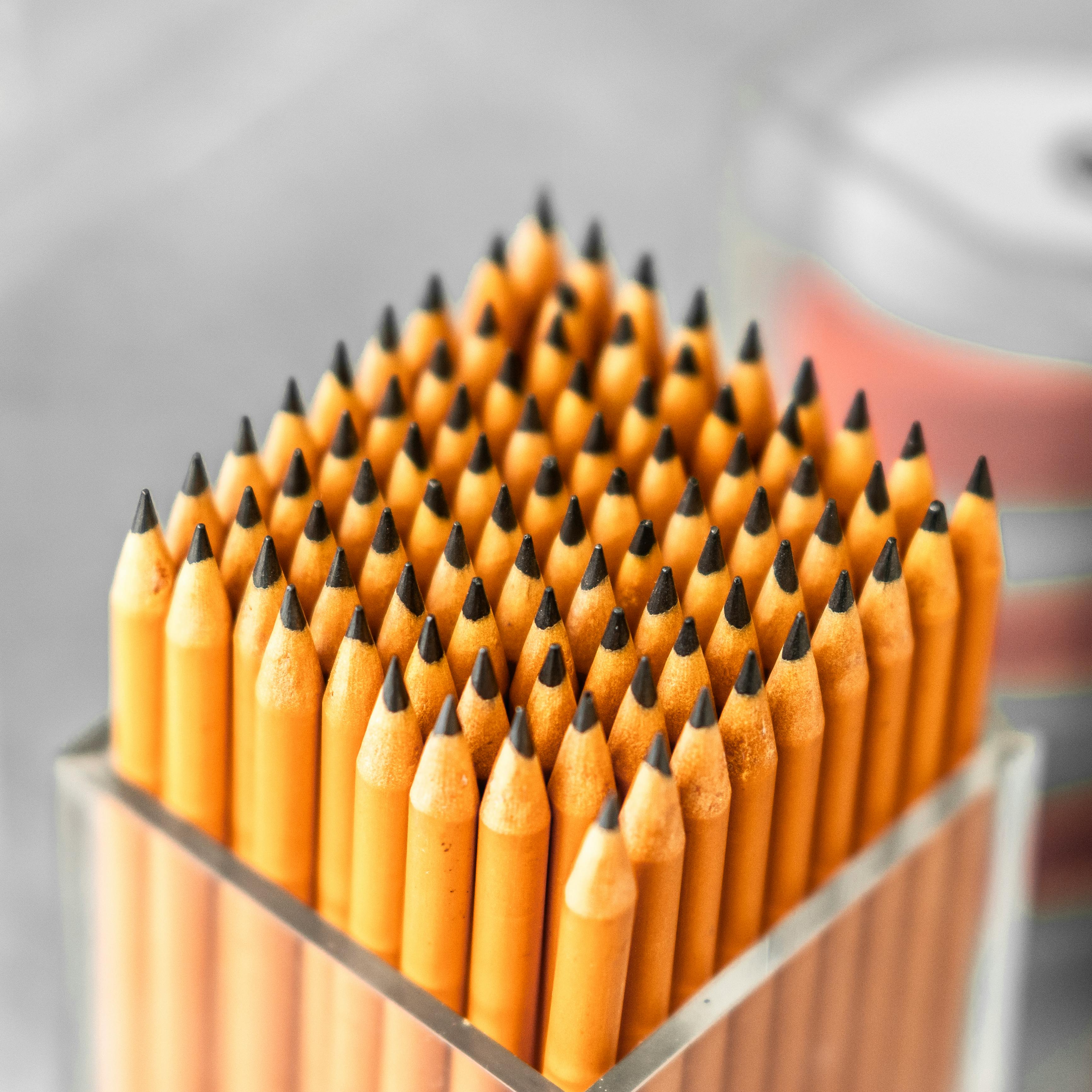 A collection of sharpened yellow pencils neatly arranged in a transparent holder.