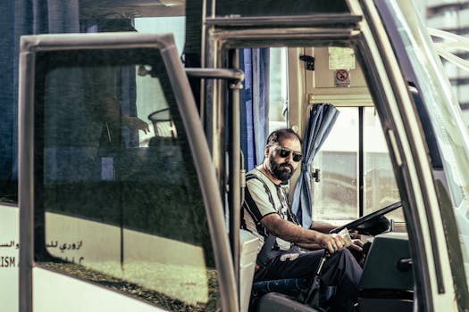 Photo by aboodi vesakaran Confident bus driver in sunglasses sits behind the wheel, ready for travel.
