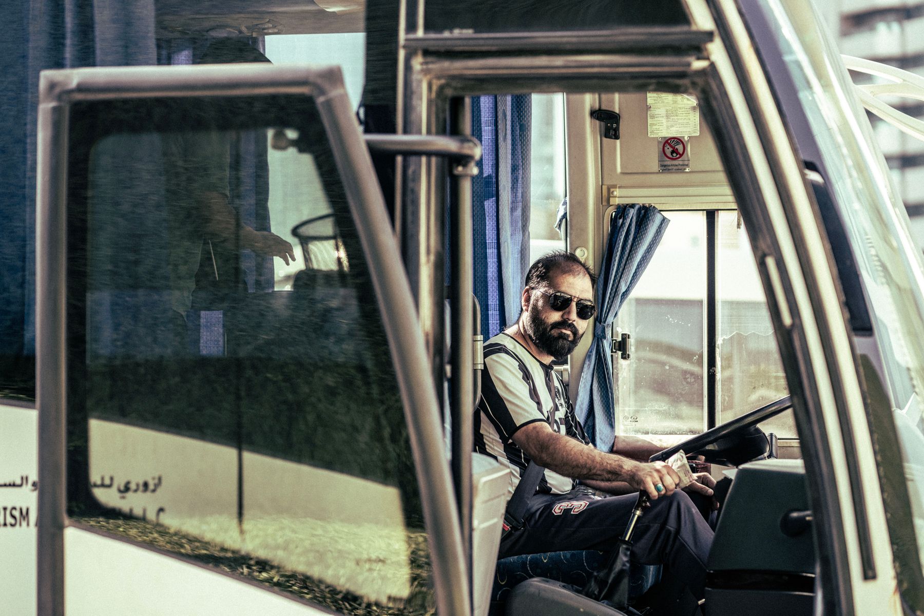 Conductor al volante de un bus, visto desde la puerta delantera