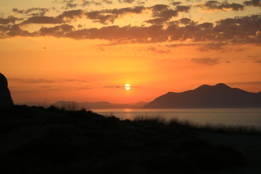 Vibrant sunset view with mountains and lake, perfect for tranquil and nature themes.
