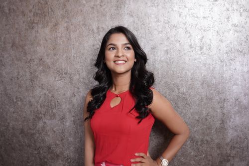 Free Young woman in red dress smiling against gray background. Stock Photo