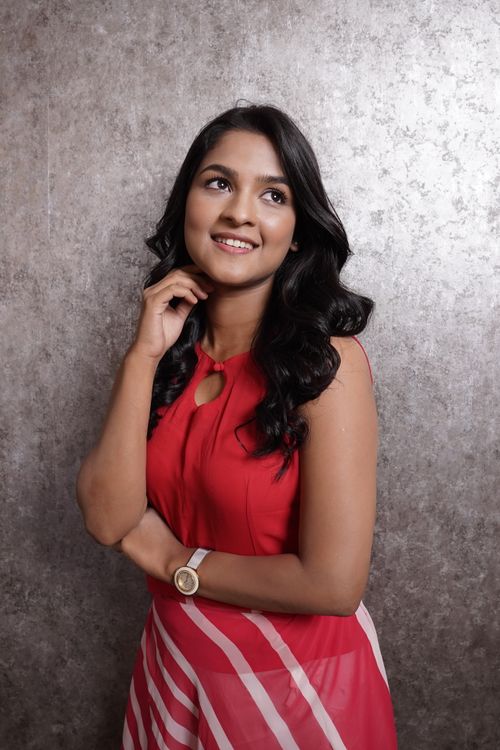 Free Portrait of a smiling woman in a red dress posing against a textured studio background. Stock Photo