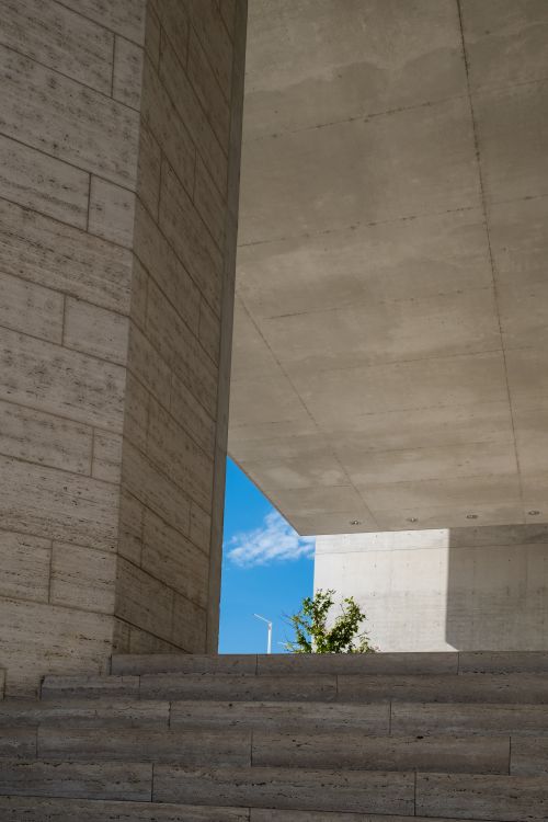 Free A staircase leading through modern concrete buildings with a glimpse of blue sky above. Stock Photo