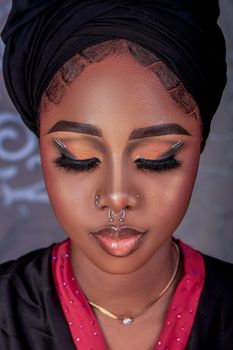 Striking close-up portrait of a woman showcasing bold makeup and facial piercings.