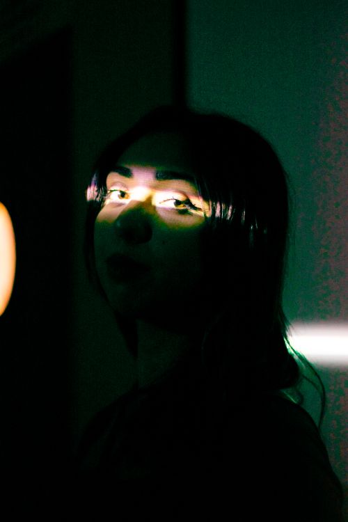 Free Mysterious portrait of a woman with long hair highlighted by a narrow beam of light. Stock Photo