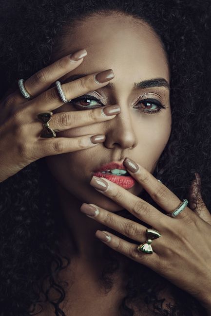 Close-up portrait of a stylish woman with elegant rings and makeup, showcasing beauty and fashion.
