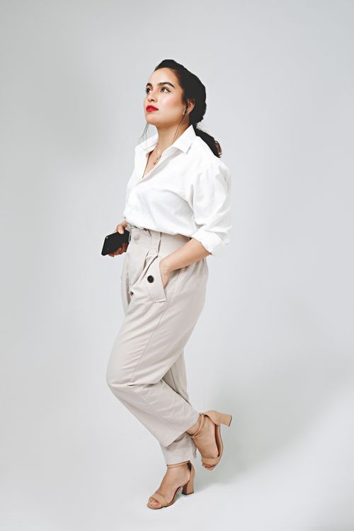 Free Elegant woman in fashion attire stands holding a smartphone, exuding confidence. Stock Photo