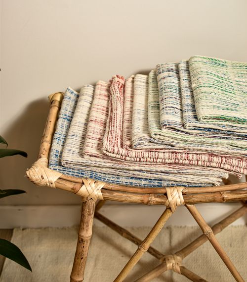 Free A stack of colorful handwoven textiles on a bamboo chair, showcasing traditional craftsmanship. Stock Photo