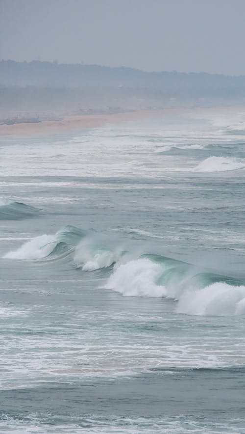 Free A surfer rides a wave on a beach in the rain Stock Photo