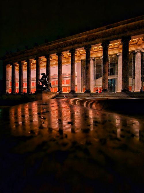 Free Stunning night view of an illuminated museum facade with columns reflecting on wet surface in Berlin. Stock Photo