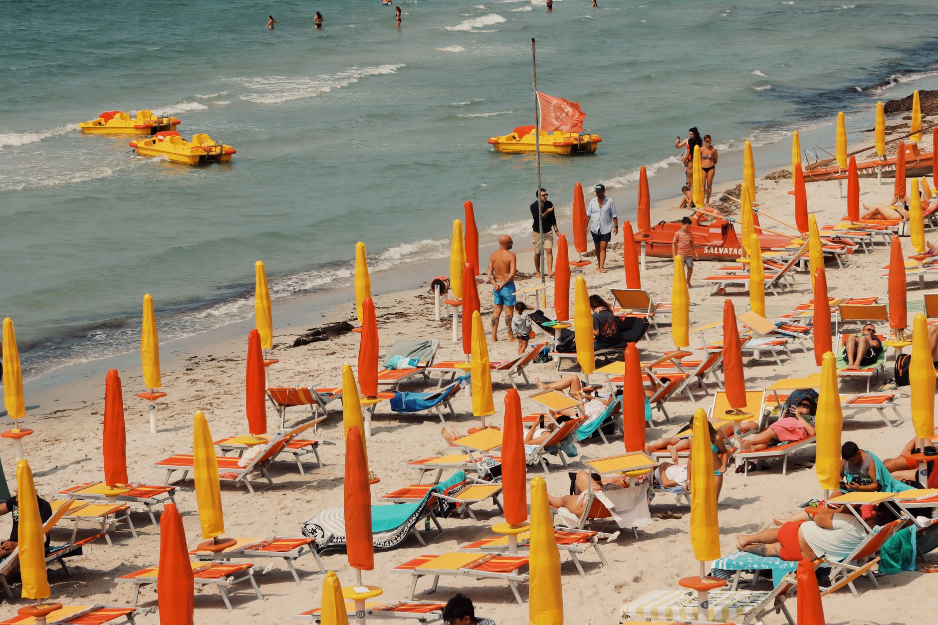 Vibrant Sardinian beach with colorful umbrellas and sunbeds under the summer sun.