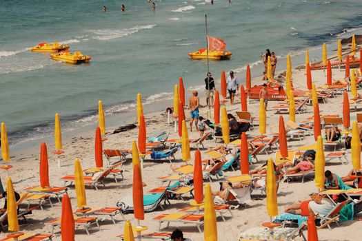 Vibrant Sardinian beach with colorful umbrellas and sunbeds under the summer sun.