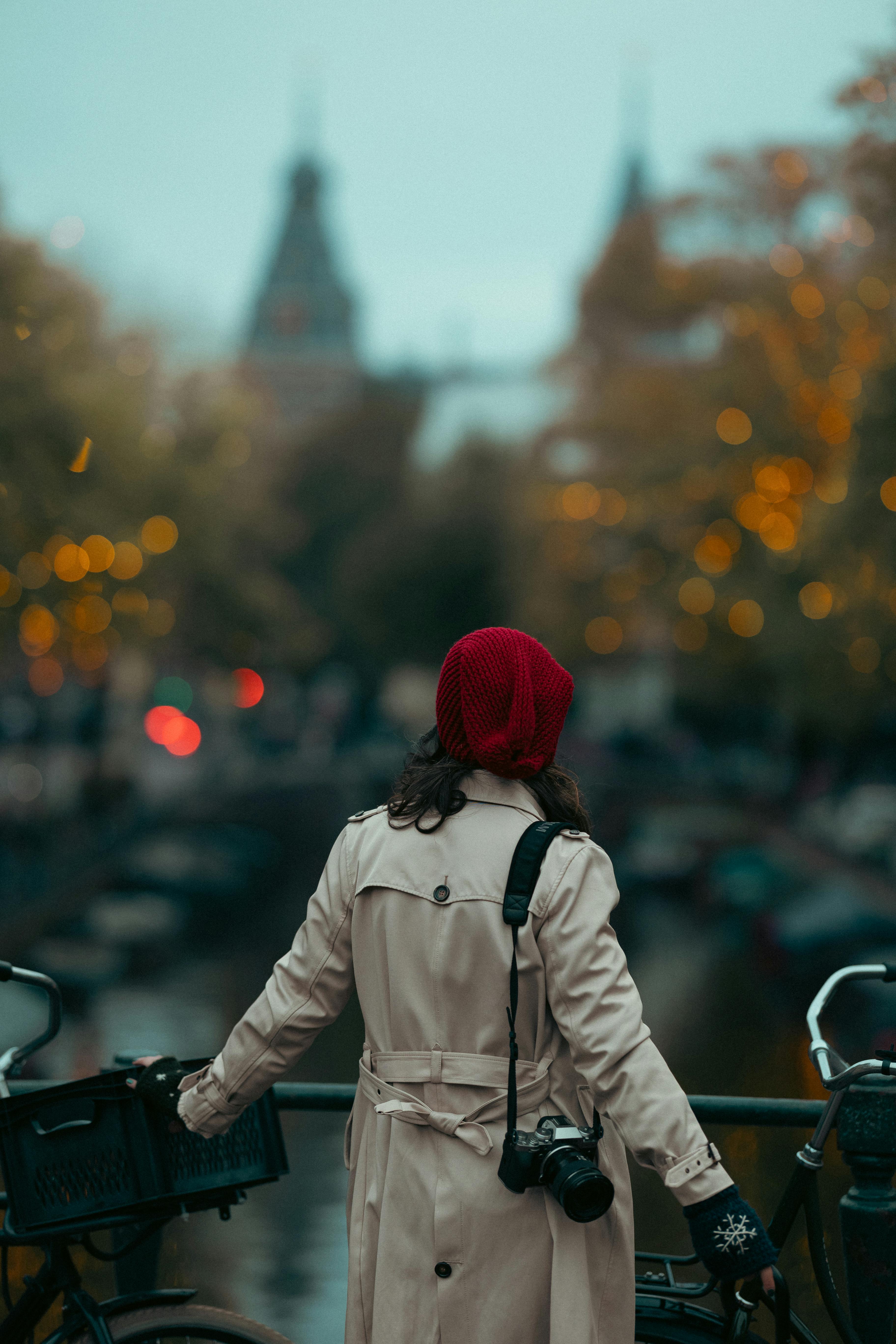 Stylish woman with camera in Amsterdam, capturing a warm evening by the canal.