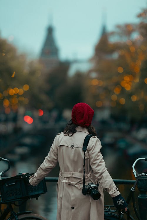 Woman in Beige Coat Standing on Bridge in Amsterdam, Netherlands