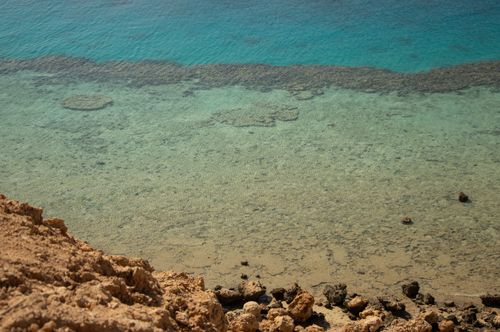 Free Scenic view of a tranquil beach with clear aqua waters and rocky shoreline. Stock Photo