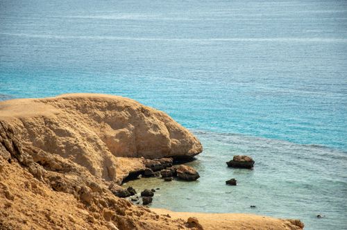 Free Peaceful coastal scene featuring sandstone cliffs and clear blue seawater under a summer sky. Stock Photo