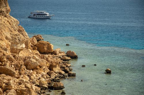 Free Eroded cliffs and a yacht on the clear blue sea create a serene coastal scene. Stock Photo