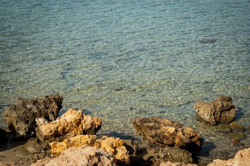 Free A serene view of the clear sea water with rocky formations along the shore, depicting natural beauty. Stock Photo