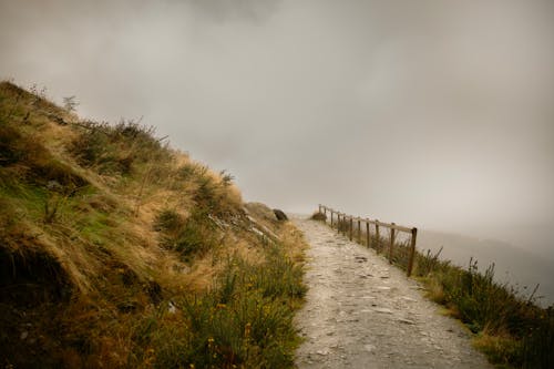 Fenced Trail Leading along a Mountain Edge in Fog