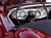 经典红色敞篷车的仪表板特写，配有复古速度表和方向盘