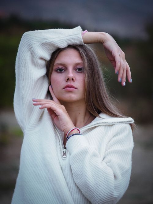 Free Portrait of a stylish woman posing outdoors in a white pullover, exuding confidence and modern fashion sense. Stock Photo