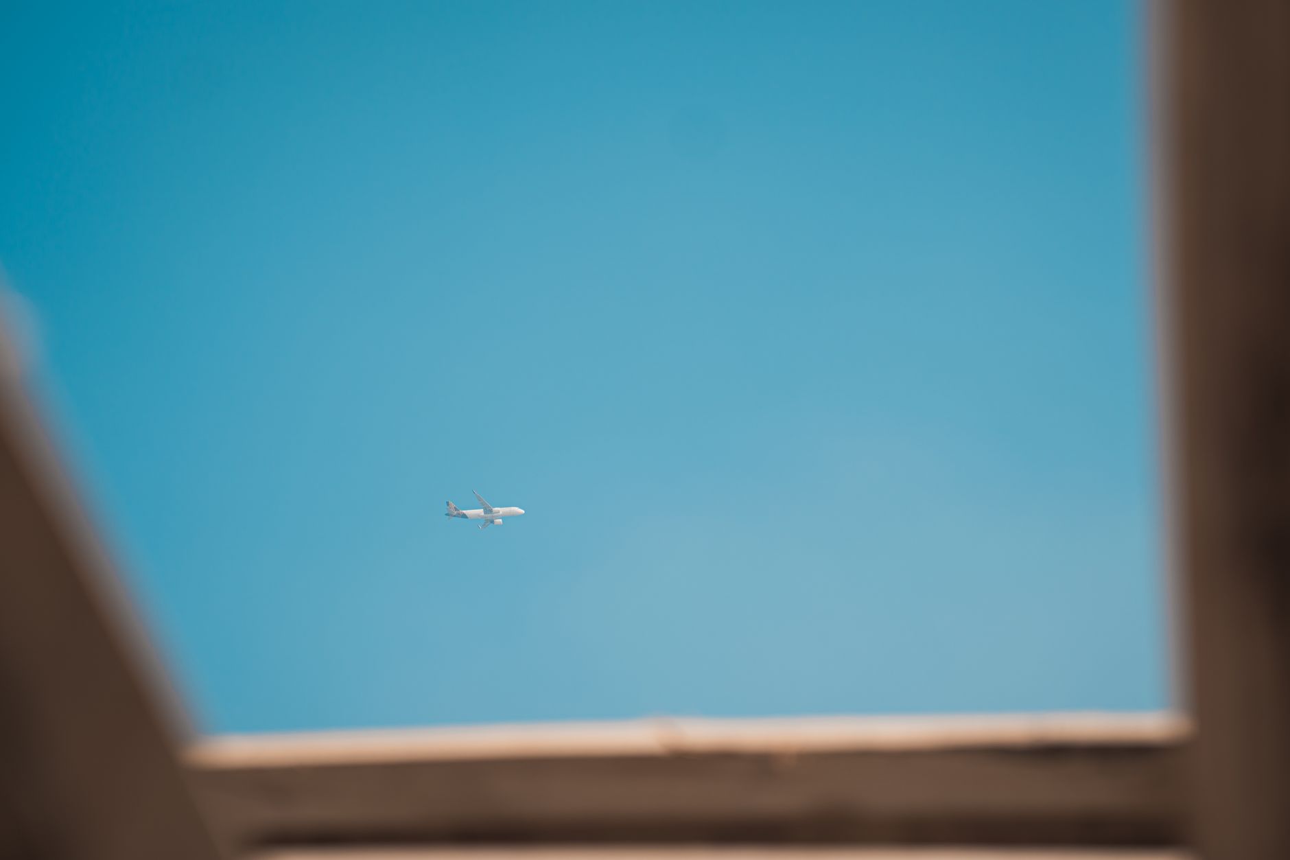A distant airplane flying in a bright blue sky, viewed from Srinagar.