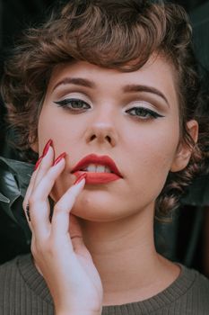 Close-up portrait of a woman with bold red lipstick and elegant makeup, embodying classic beauty.