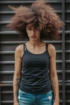 一位留着浓密卷发的年轻女子，身穿休闲黑色背心和牛仔裤