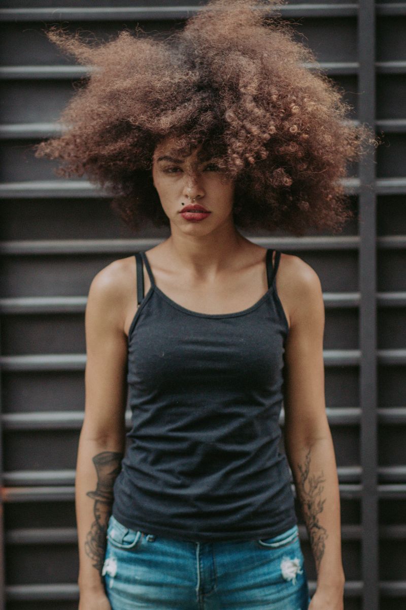Young woman with voluminous curly hair in a black top and jeans