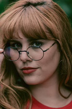 一位戴眼镜的红发女子特写肖像，展现优雅与时尚