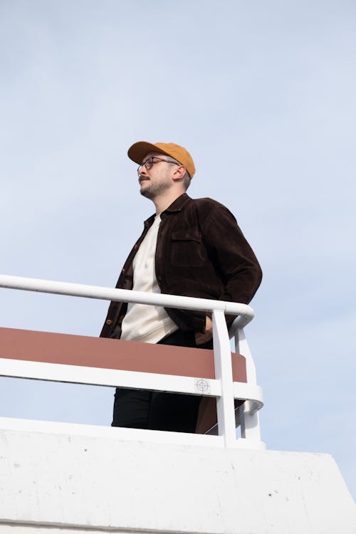 Man in Brown Baseball Cap Standing on Ship Deck