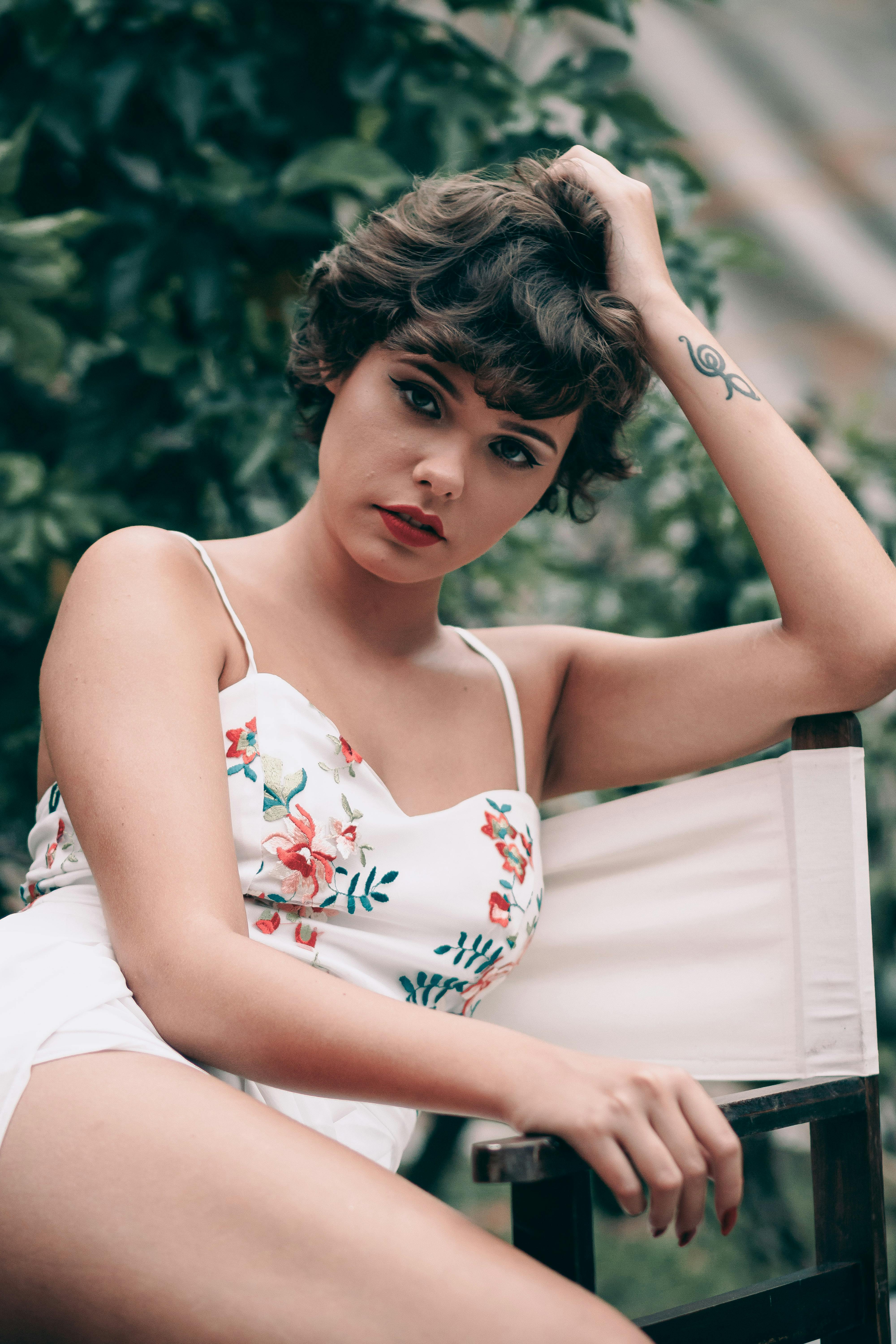 一位时尚女性留着短发，穿着花卉上衣，在夏季的户外摆姿势