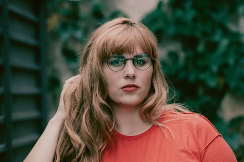 Photo of Woman in Eyeglasses Touching Her Hair With Her Left Hand