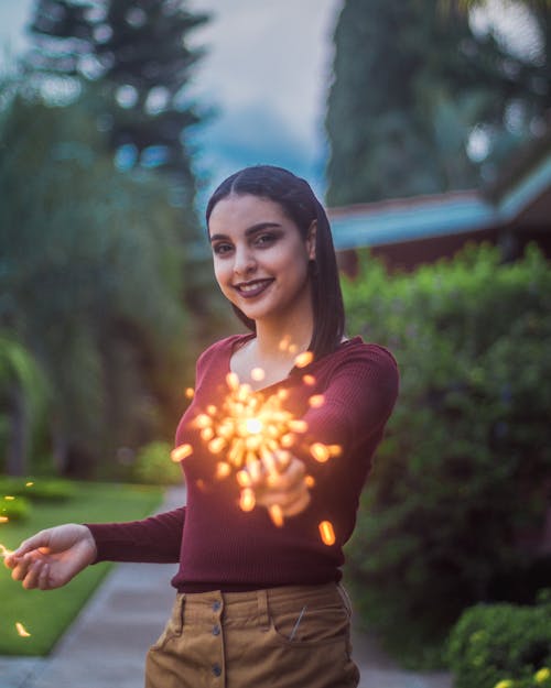 Free Photo of Smiling Woman Standing while Holding Sparklers Stock Photo